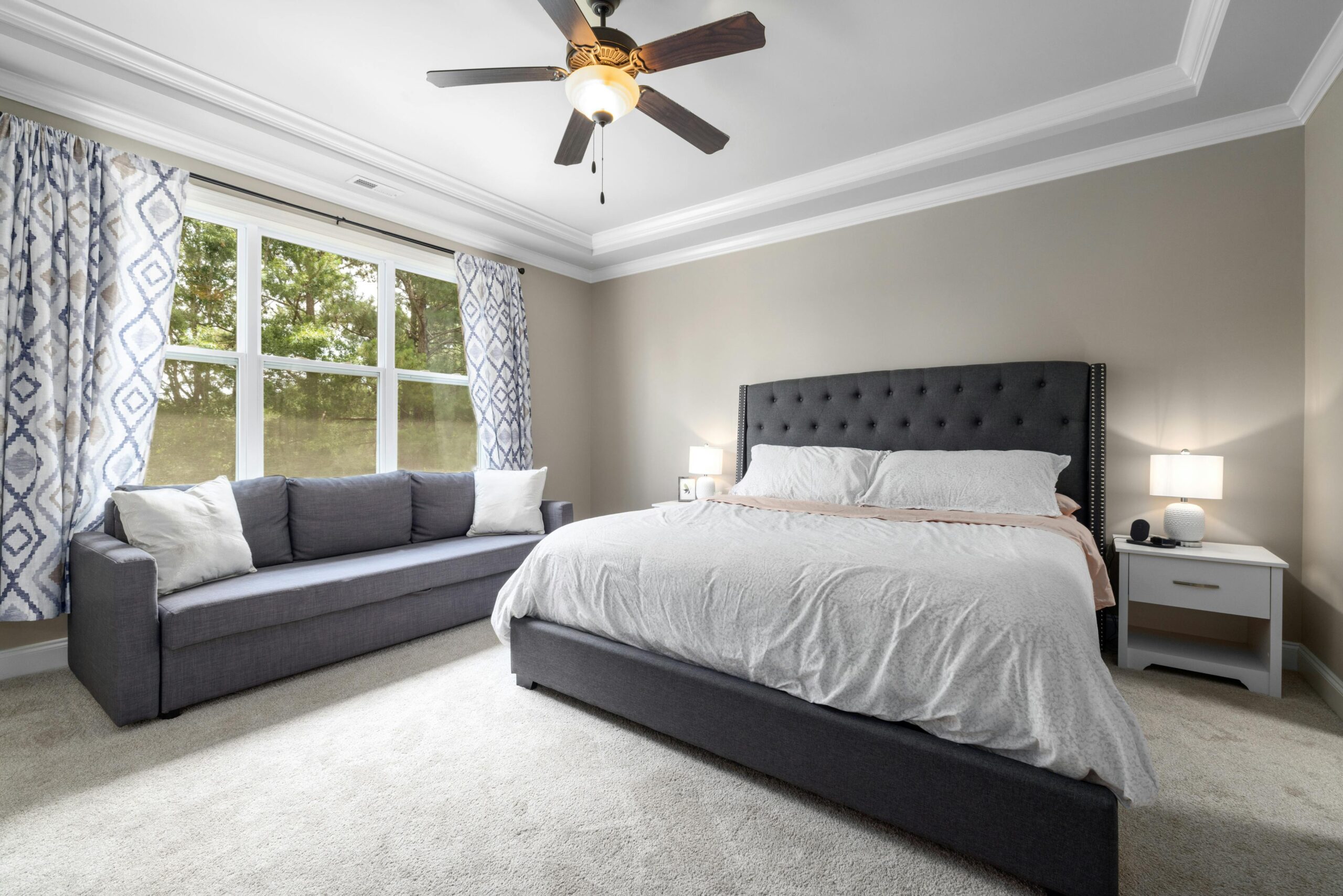 Minimalist bedroom featuring a king-sized bed, elegant furniture, and natural light through large windows.